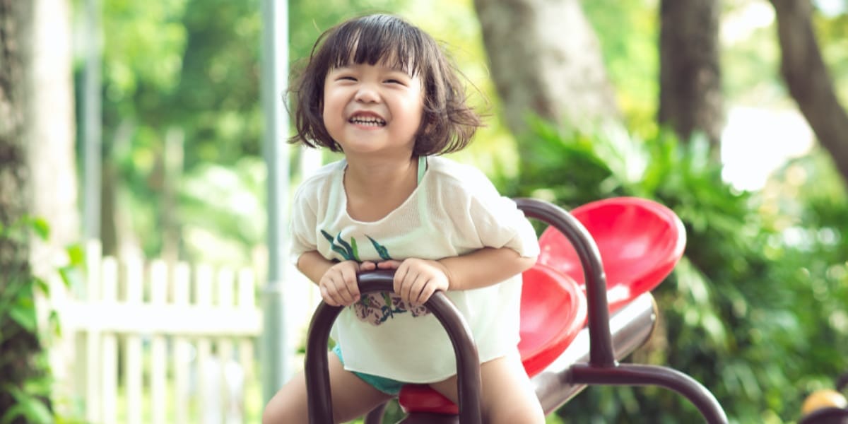 A young Asian girl smiling and enjoying herself on a playground